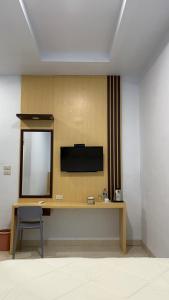 TigarasにあるSejahtera Beach Hotelの鏡付きのデスク、壁掛けテレビが備わります。