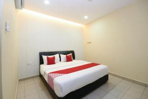 a bedroom with a large bed with red pillows at Hotel O Ys Inn in Miri