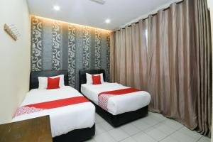 two beds in a hotel room with red pillows at Hotel O Ys Inn in Miri