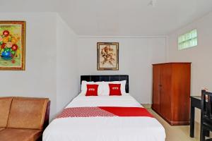 a bedroom with a bed with two red pillows at Hotel O Gusti Residence in Dalung +30 photos