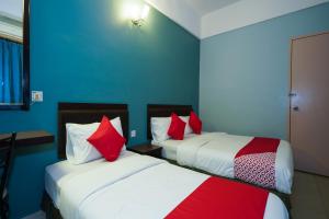 two beds in a room with blue walls and red pillows at Hotel O Hotel Orchard Inn in Lumut