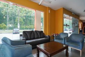 a living room with a couch and two chairs and a table at Hotel O Hotel Orchard Inn in Lumut