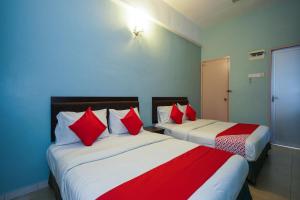 two beds in a room with red and white pillows at Hotel O Hotel Orchard Inn in Lumut +36 photos