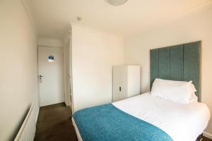a bedroom with a white bed and a green headboard at The Douglas Hotel in Hartlepool