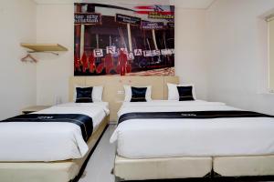two beds in a room with a poster on the wall at Townhouse Oak Cihampelas Near Ciwalk Formerly Promenade Hotel in Bandung +107 photos