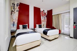 two beds in a room with red and white walls at Townhouse Oak Cihampelas Near Ciwalk Formerly Promenade Hotel in Bandung