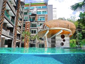 a swimming pool with a house in front of a building at Emerald Patong 1 bedroom Modern Apartment in Patong Beach