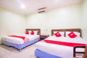 two beds in a room with red and white pillows at Hotel O Casavilla Hotel in Batu Caves