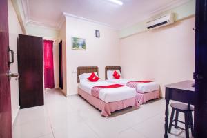 a bedroom with two beds and a desk in it at Hotel O Casavilla Hotel in Batu Caves