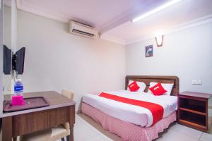 a bedroom with a bed and a desk with a computer at Hotel O Casavilla Hotel in Batu Caves