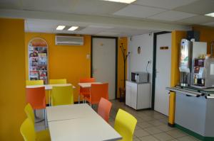 a dining room with tables and chairs and yellow walls at Premiere Classe Chambery in Chambéry