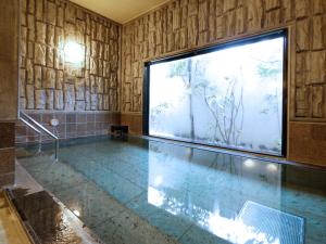 a swimming pool with a large screen in a room at Hotel Route-Inn Odate Omachi in Odate