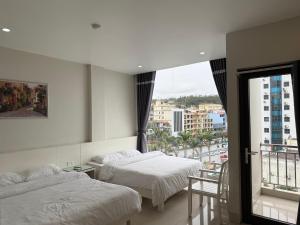 a hotel room with two beds and a balcony at MeKong Hotel in Ha Long