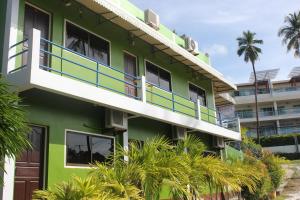 a green building with a balcony and palm trees at Vacation House in Klong Muang Beach