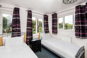 two beds in a room with two windows at Chris's Motel in Stokenchurch +41 photos