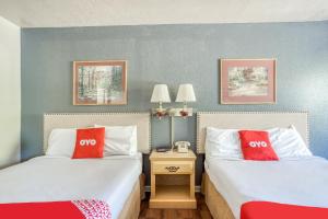 two beds in a hotel room with red pillows at OYO Hotel Heber Springs Lakeside in Heber Springs