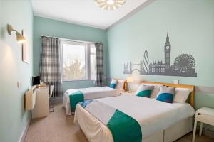 two beds in a room with blue walls at The Green Man Pub and Hotel by OYO in London