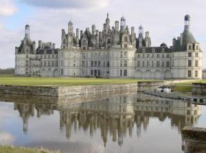 un gran castillo con su reflejo en el agua en La Maladière, en Cormeray