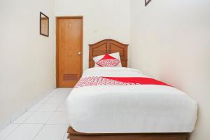 a bedroom with a bed with a red and white pillow at Hotel O Penginapan Kepurun Pawana Indonesia in Sleman