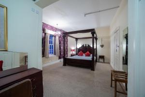 a bedroom with a canopy bed with red pillows at George Hotel, Burslem, Stoke-on-Trent in Stoke on Trent