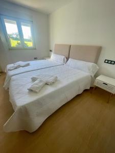 a bedroom with a large white bed with towels on it at Villa Emilio Foz in Foz