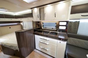a small kitchen in an rv with a bed at Domki i POKOJE PLAŻOWE in Darlowko