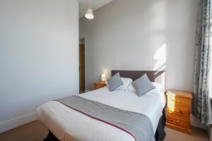 a bedroom with a large white bed with blue pillows at OYO Shanklin Beach Hotel in Shanklin