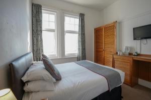 a bedroom with a bed and a window and a television at OYO Shanklin Beach Hotel in Shanklin