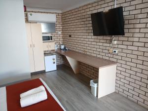 a small kitchen with a counter and a tv on a brick wall at Alfa motel in Gilgandra