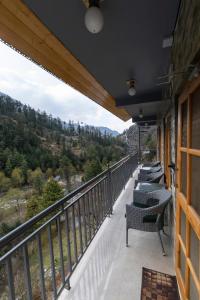 a balcony with chairs and a view of the mountains at Eden Stay & Cafe in Jibhi