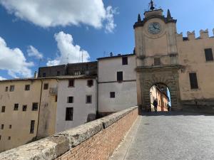 an old building with a clock tower and a wall at I Colori nel Castello Capranica in Capranica