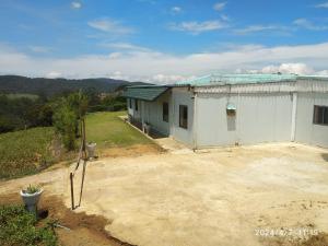 a large white building with a field in front of it at Kitty cointainer bungalow ambewela - kcb ambewela in Nuwara Eliya