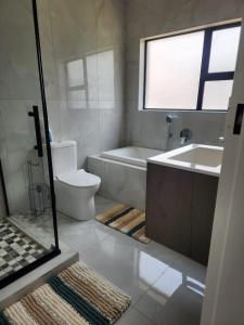 a bathroom with a tub and a toilet and a sink at Ee40Yethu in Pretoria +8 photos