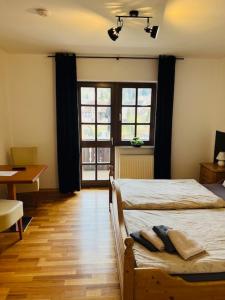 a bedroom with a bed and a desk and windows at Landhaus Magnus in Ramberg