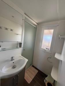 een badkamer met een wastafel, een spiegel en een raam bij Ô Coeur d'Eden ,2 mobilhomes l'Ôriginal et le BÔ'Aime in Piriac-sur-Mer