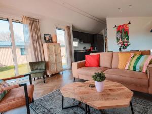 a living room with a couch and a table at Nieuwe Luxe Lodge met Weidezicht - bij Nationaal park Drents-Friese Wold in Hoogersmilde