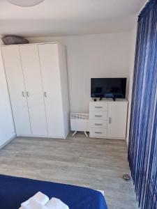 a bedroom with a bed and a tv and white cabinets at Apartmani Krepelnik in Drage