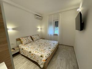 a small bedroom with a bed and a television at Apartments Demarin in Medulin