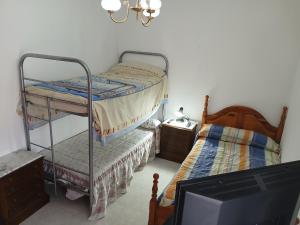 a bedroom with two bunk beds and a tv at Habitacion Privada Triple con camas Individuales Toledo in Toledo