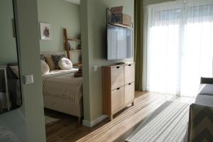 a bedroom with a bed and a flat screen tv at Neringarent STUDIO-APARTAMENTAI in Juodkrantė