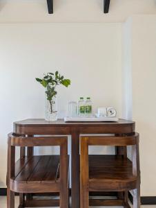 a wooden table with two stools and a vase on top at Nildiya Cottages in Elpitiya
