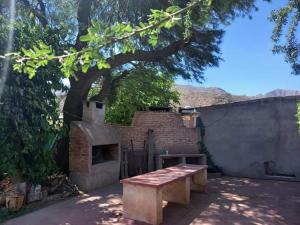 a wooden bench in front of a brick building with a fireplace at María del Valle Alojamientos in Belén