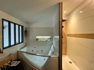 une grande salle de bain avec baignoire et douche dans l'établissement Love Room Loft Spa logement entier balneo exterieur, à Ambronay 27 autres photos