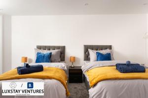two beds in a room with blue pillows at Bright and Spacious 2BR Maisonette Sleeps 8, Game Room, 5 mins to Brighton Beach and City Centre in Brighton & Hove