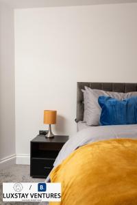 a bedroom with a bed with a yellow blanket and a lamp at Bright and Spacious 2BR Maisonette Sleeps 8, Game Room, 5 mins to Brighton Beach and City Centre in Brighton & Hove