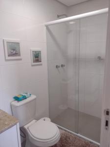 a bathroom with a toilet and a glass shower at Apto vista magnífica condomínio familiar Floripa in Florianópolis