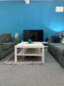 sala de estar con mesa de centro blanca y 2 sofás en The Netflix Suite, en Leicester