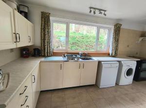 a kitchen with a sink and a washing machine at Smithy Cottage in Blairgowrie