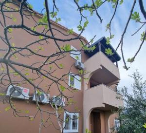 a building with a balcony with a clock on it at Lavanda Apartments in Pakoštane