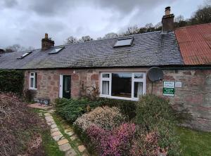a brick house with a window and a roof at Smithy Cottage in Blairgowrie
